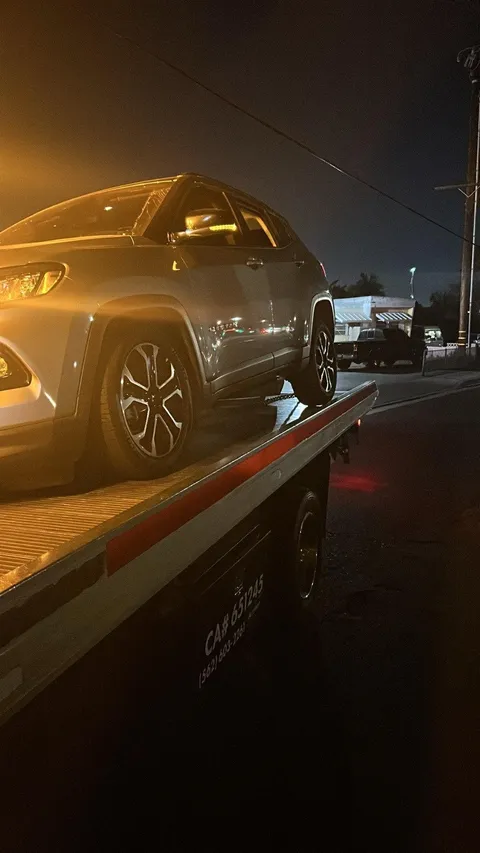 Gray car loaded on flatbed tow truck at night in East Whittier California