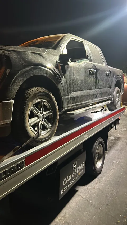 Nighttime flatbed towing showing side view of a vehicle being transported after breakdown in Hawaiian Gardens, CA.