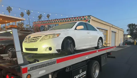 White car being towed on flatbed tow truck in La Habra Heights California afternoon