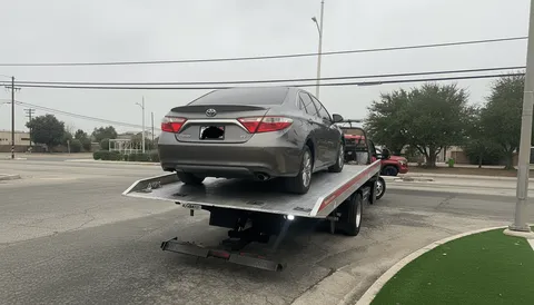 Gray vehicle being towed afternoon roadside in Lakewood California