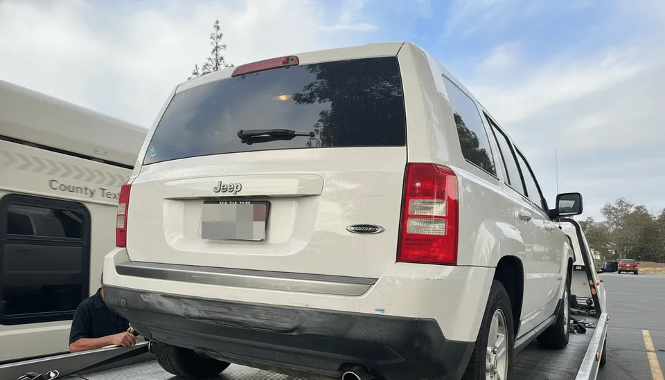 Tow truck transporting broken-down white van in Cypress California daytime