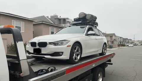White car on flatbed tow truck on highway daytime in Paramount California