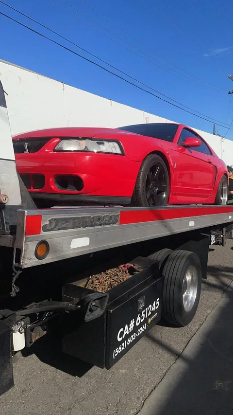 Tow truck loading a red car on a sunny day in Artesia, California.