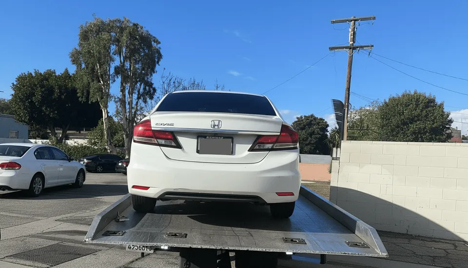 White car on flatbed tow truck daytime in Lakewood California