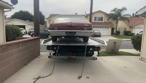 Tow truck lifting rusty car in garage during daytime in Garden Grove California