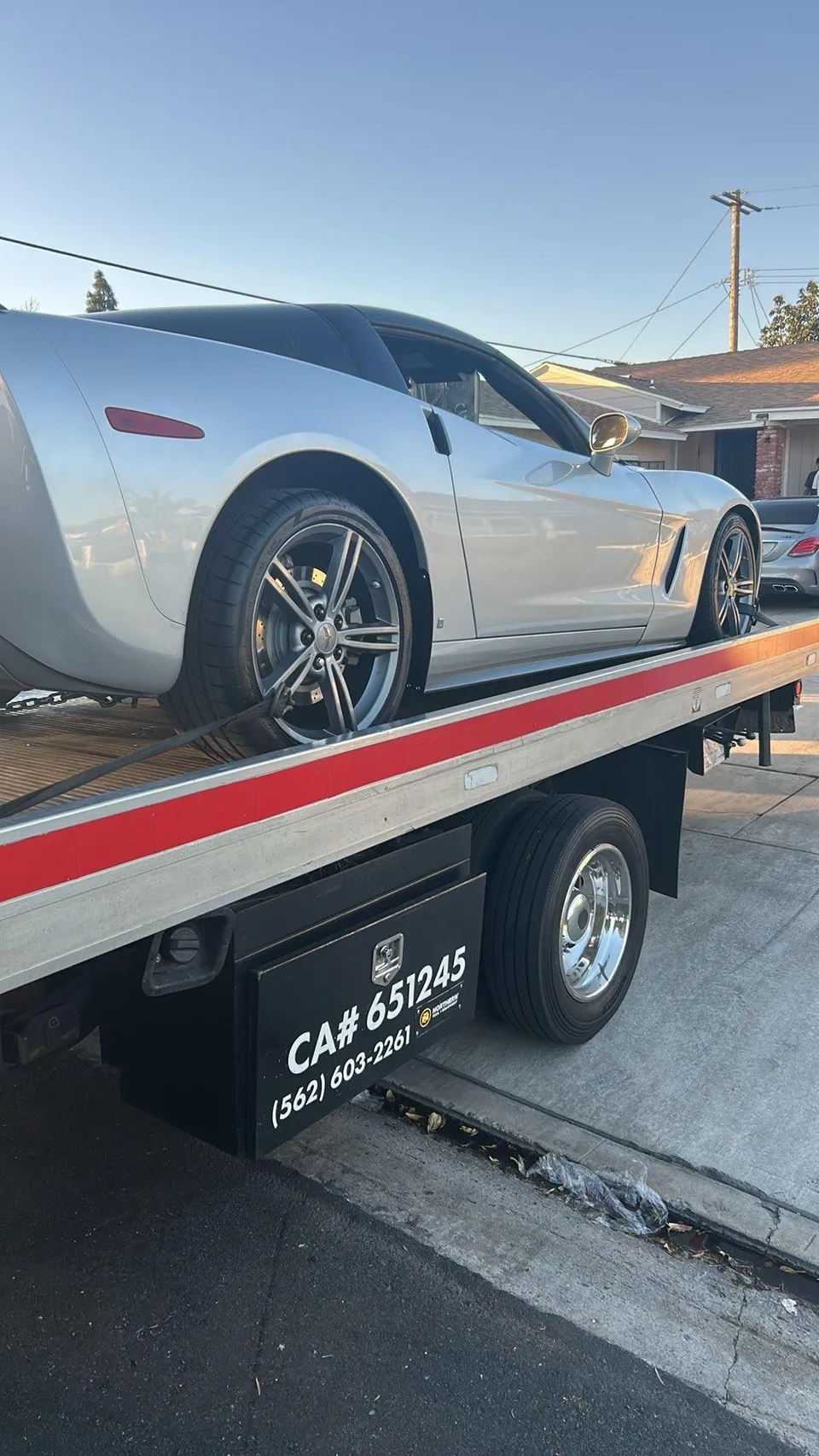 Flatbed tow truck loading broken down car during daytime in Bell Gardens California
