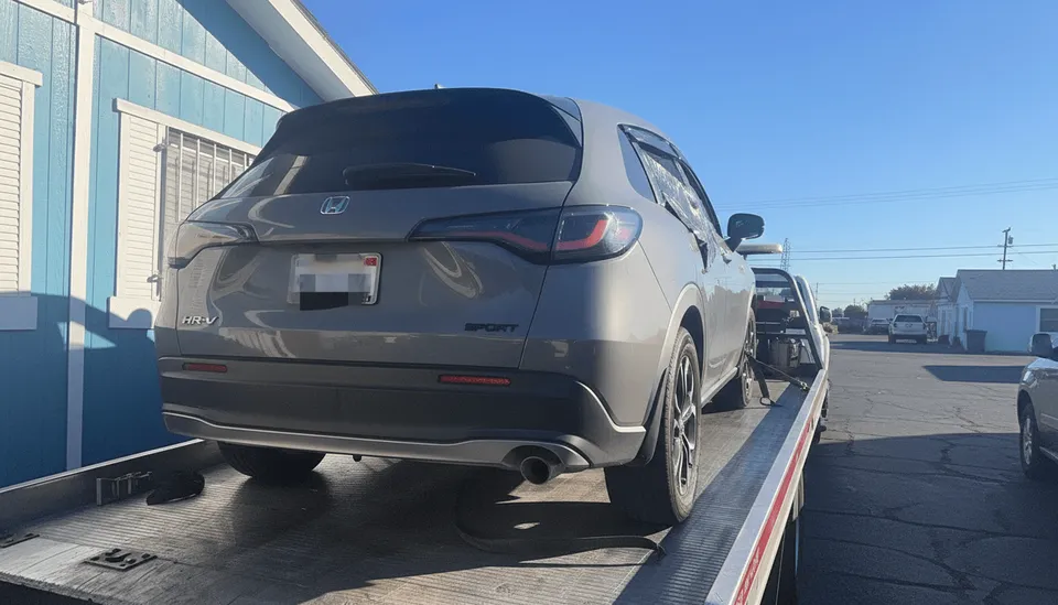Gray car secured on flatbed tow truck parked in Irvine California daytime