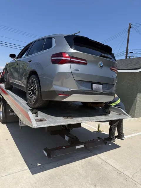 Red towing operator loading a BMW X3  in Downey, CA for a gray BMW X3 July 2026