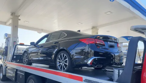 Black car being towed at gas station in Long Beach California