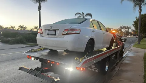 White car on flatbed tow truck on highway in La Habra California afternoon