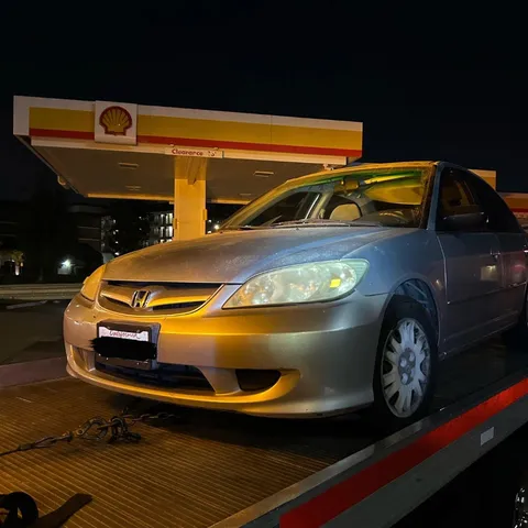 Flatbed tow truck picking up a non-running car during nighttime in Anaheim, California.