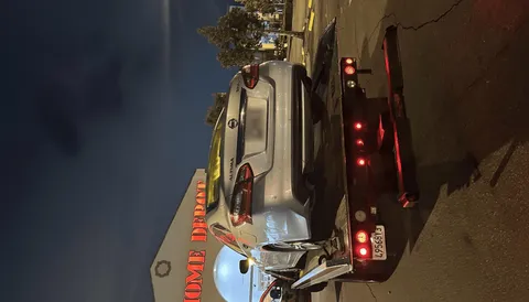 Gray car on tow truck at night in commercial parking area in La Habra Heights California