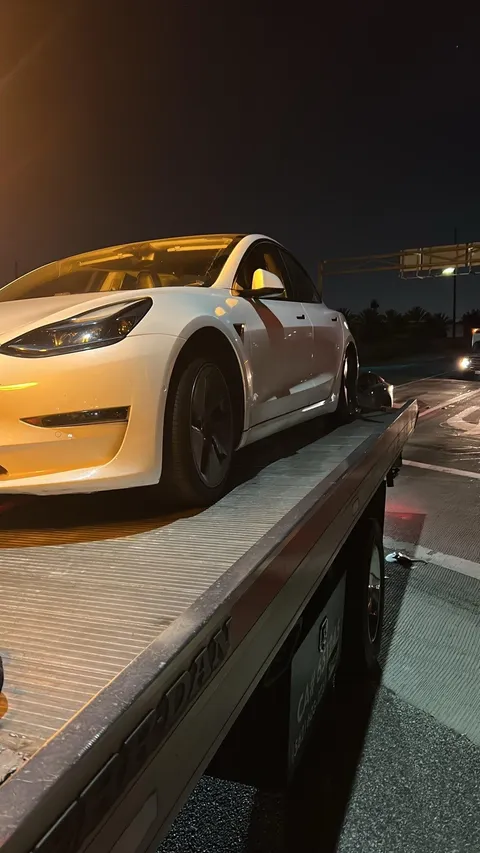 Tow truck loading white sports car at night in Cypress California
