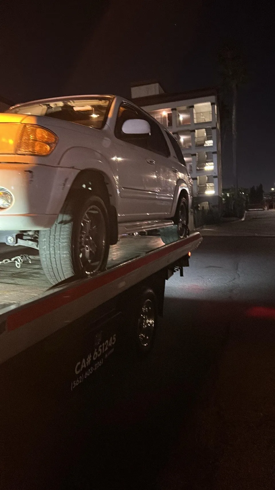 White car on flatbed tow truck at night in East Whittier California