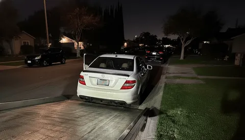 White car being unloaded from flatbed tow truck at night in Hacienda Heights California