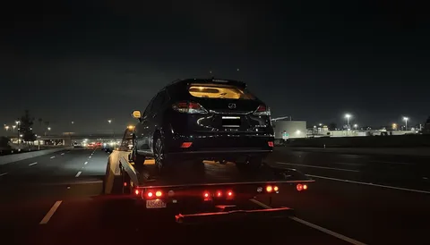 Black car being towed on highway at night in La Habra California
