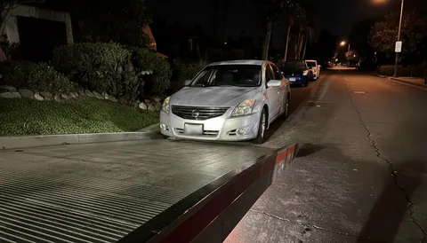 White car loading onto tow truck at night in Long Beach California