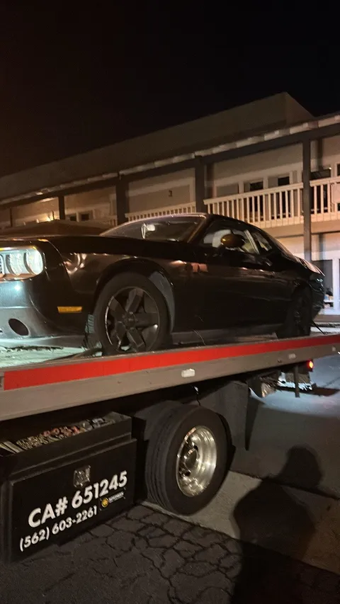 Car secured on flatbed tow truck at night in La Palma California
