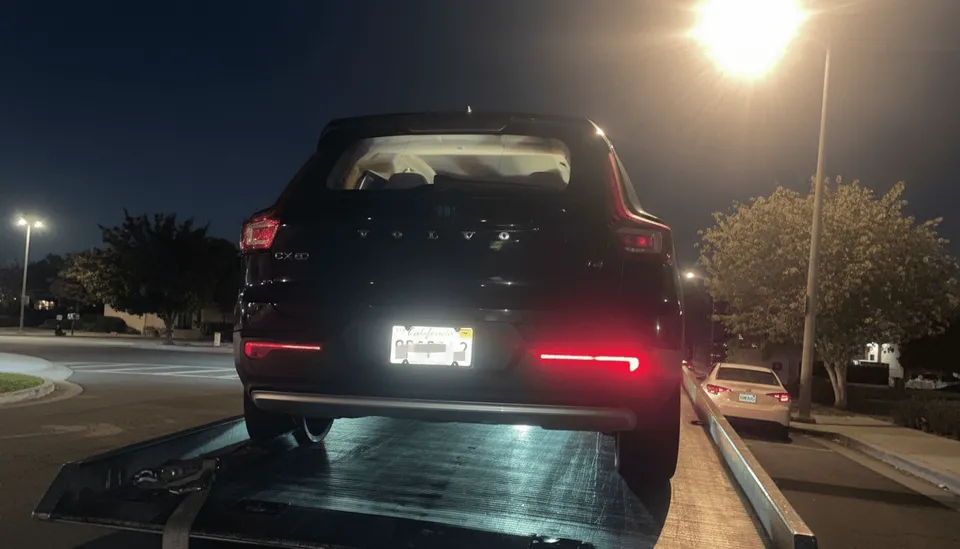 Tow truck transporting a black vehicle during nighttime roadside assistance in Orange County, California.