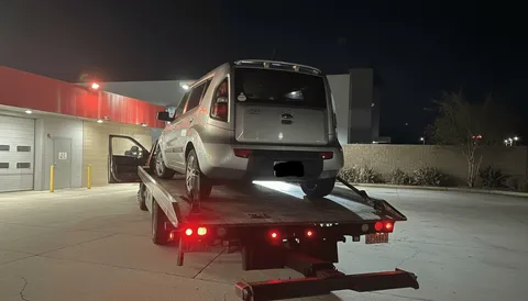 Gray car being towed on flatbed tow truck at night in Seal Beach California