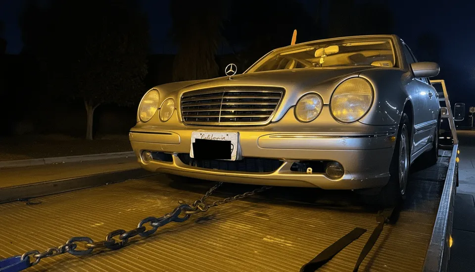 Gray car being towed at night on flatbed tow truck in South Whittier California