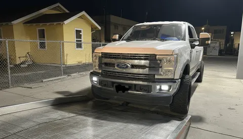 White van being towed at night on flatbed tow truck in Stanton California
