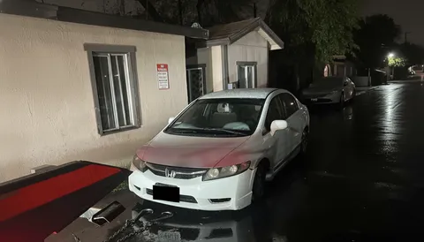 hite car being loaded onto tow truck in parking area in Hacienda Heights California, side view