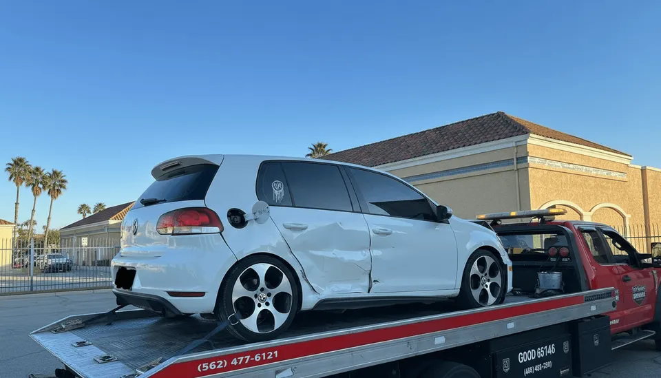 White car being towed from house on flatbed tow truck in Stanton California