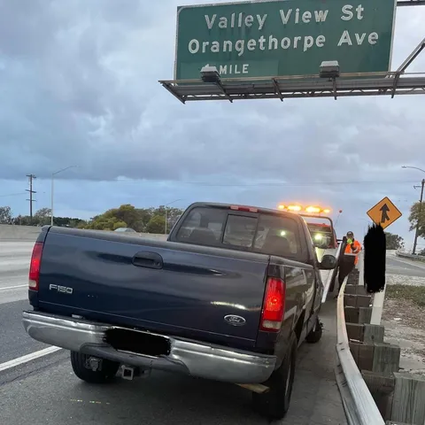 Tow truck assisting stalled pickup vehicle in Buena Park CA daytime