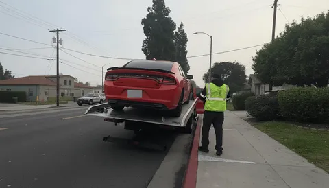 Tow truck helping stalled red car in the road in Irvine California daytime