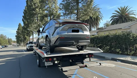 Black car being towed on city road in La Mirada California daytime
