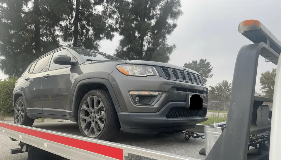 Gray car on flatbed tow truck during twilight in La Habra California