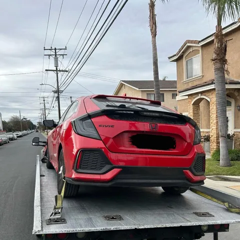 Tow truck unloading broken down car after tow in Bellflower California