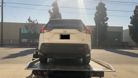White car towed and parked on flatbed tow truck in Santa Ana California