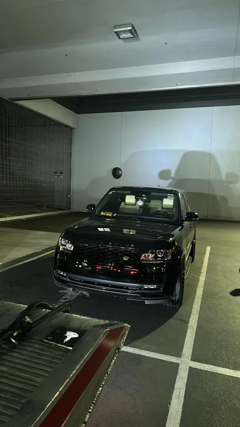 Black car being unloaded from flatbed tow truck in Downey California