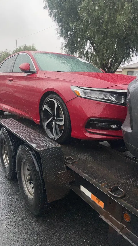 Red car coming down from flatbed tow truck in La Palma California