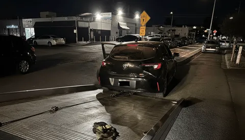 Black car recently unloaded from a tow truck after towing service in Riverside County, California.